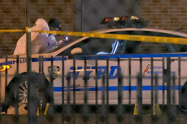 An investigator at the scene where two police officers were fatally shot in Brooklyn on Saturday. Credit John Minchillo/Associated Press