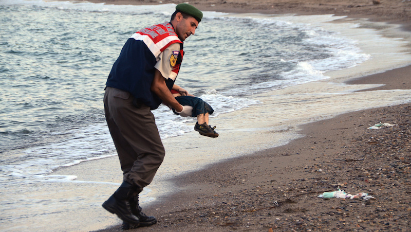 A paramilitary police officer carries the lifeless body of Aylan Kurdi. (AP Photo/DHA)