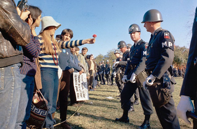 A female demonstrator offers a flower to military police on guard at the Pentagon during an anti-Vietnam demonstration. Arlington, Virginia, USA, 21 October 1967. By S.Sgt. Albert R. Simpson. Department of Defense. Department of the Army. Office of the Deputy Chief of Staff for Operations. U.S. Army Audiovisual Center.