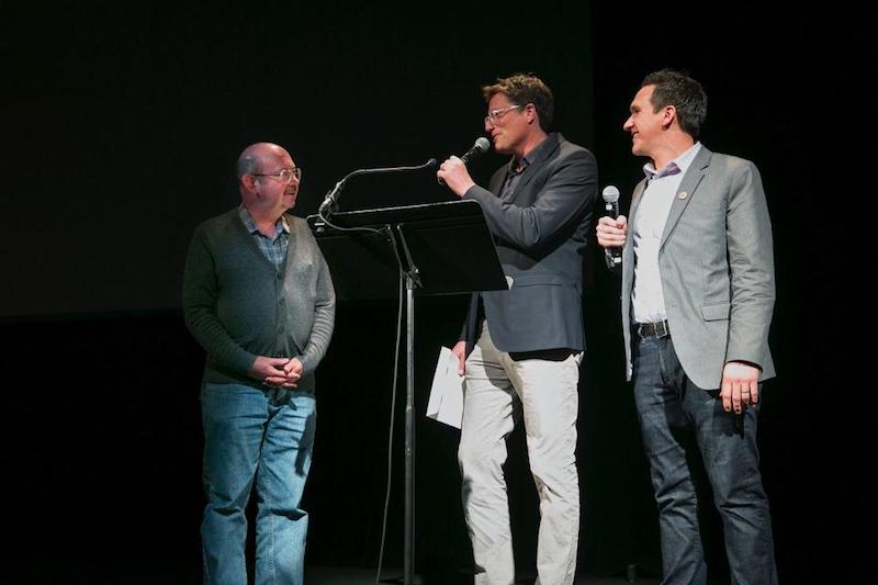UT government professor Zach Elkins and KUT's Matt Largey present Gregory (left) with his new grade at the Paramount Theatre in Austin. CREDIT ILANA PANICH-LINSMAN FOR POP UP MAGAZINE