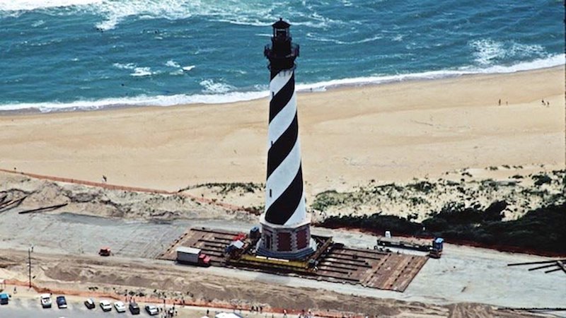 Above: An excellent example of a well-managed strategic retreat from the coast occurred in 1999, when the Cape Hatteras Lighthouse on North Carolina’s Outer Banks was moved 2,900 feet back from an eroding shoreline, a move that cost $12 million. When completed in 1870, the Cape Hatteras lighthouse had been located a safe 1,500 feet inland from the ocean, but natural barrier island erosion processes, augmented by rising seas and storm-driven tides, had reduced this distance to just 120 feet by 1999. Locals were strongly opposed to the move, believing it would harm the tourist industry. Ironically, the lighthouse is now more of a tourist attraction than ever. On the Outer Banks of North Carolina, the regional slope of the land is 1 to 10,000, which means in theory that a 1-foot rise in sea level could move the shoreline about 2 miles. Thus, the lighthouse will likely have to be moved again later this century. Image credit: National Park Service.