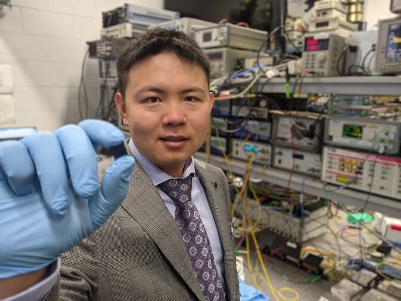 Dr Xingyuan (Mike) Xu with the integrated optical microcomb chip, which forms the core part of the optical neuromorphic processor. Credit: Swinburne University of Technology